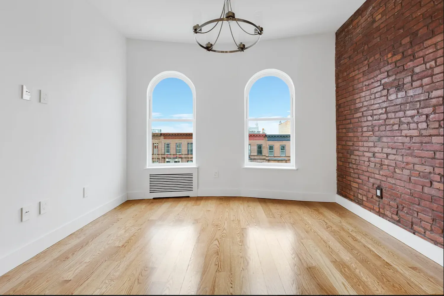 a view of an empty room with wooden floor and window