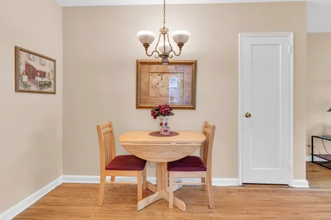 a dining room with wooden floor a chandelier a wooden table and chairs