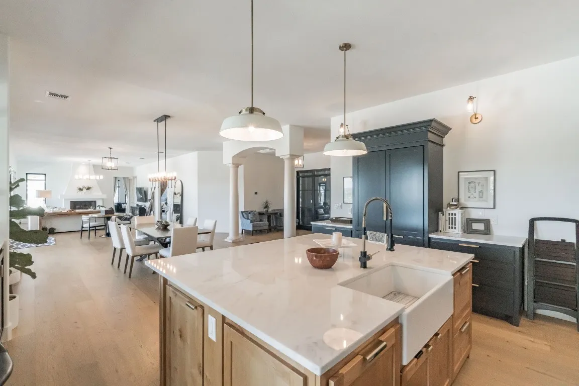 a kitchen with a stove a sink a kitchen island with chairs and wooden floor