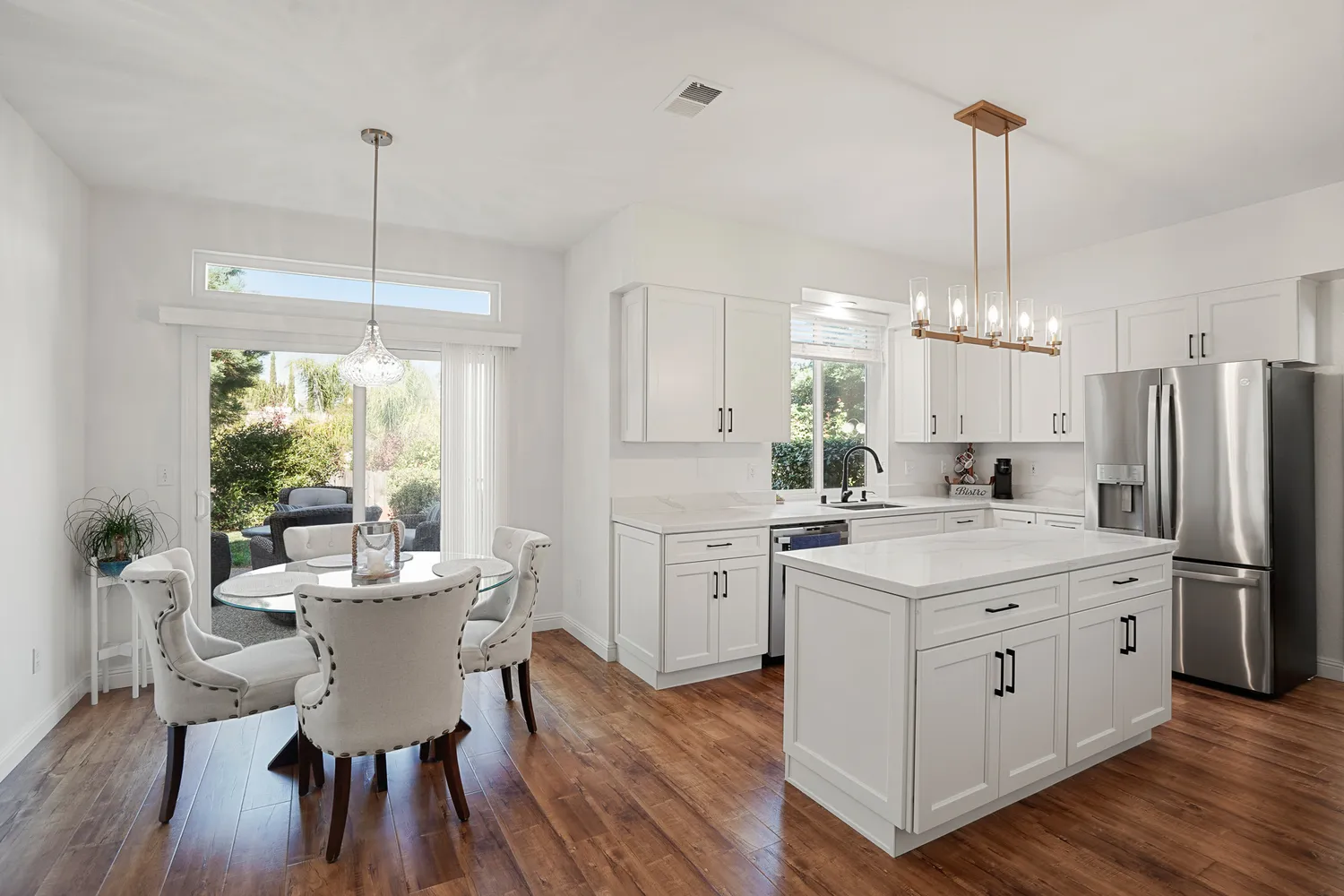 a kitchen that has a lot of white cabinets and stainless steel appliances