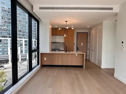 a large white kitchen with kitchen island a large window and a sink