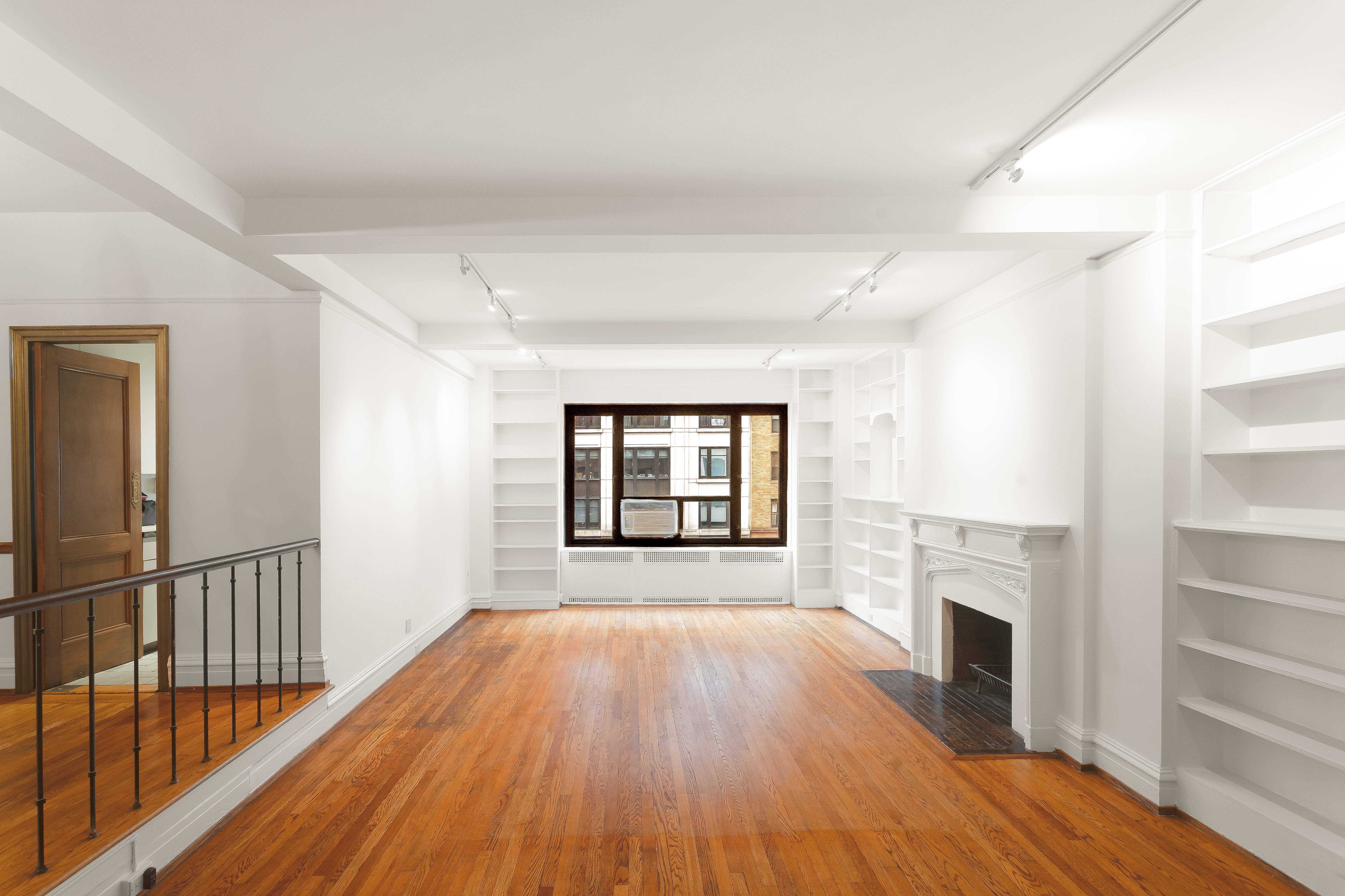 180 East 79th Street, Unit 5A Manhattan, NY 10075 - Photo 4 of 19 a view of empty room with wooden floor and fireplace