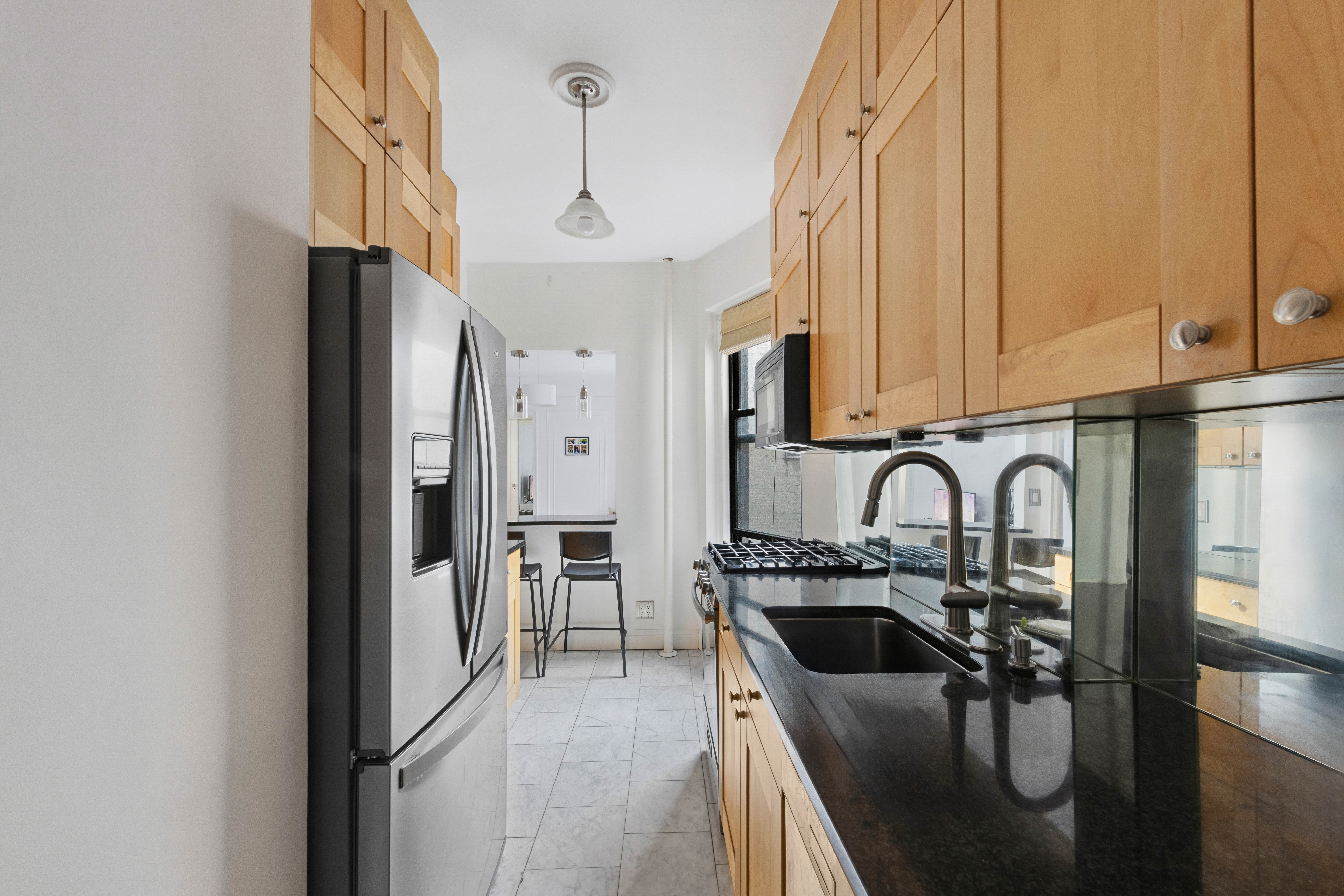 166 East 92nd Street, Unit 4C Manhattan, NY 10128 - Photo 3 of 6 a kitchen with stainless steel appliances a refrigerator a sink a stove and white cabinets