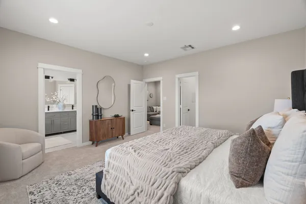 a spacious bedroom with a bed a couch and dresser