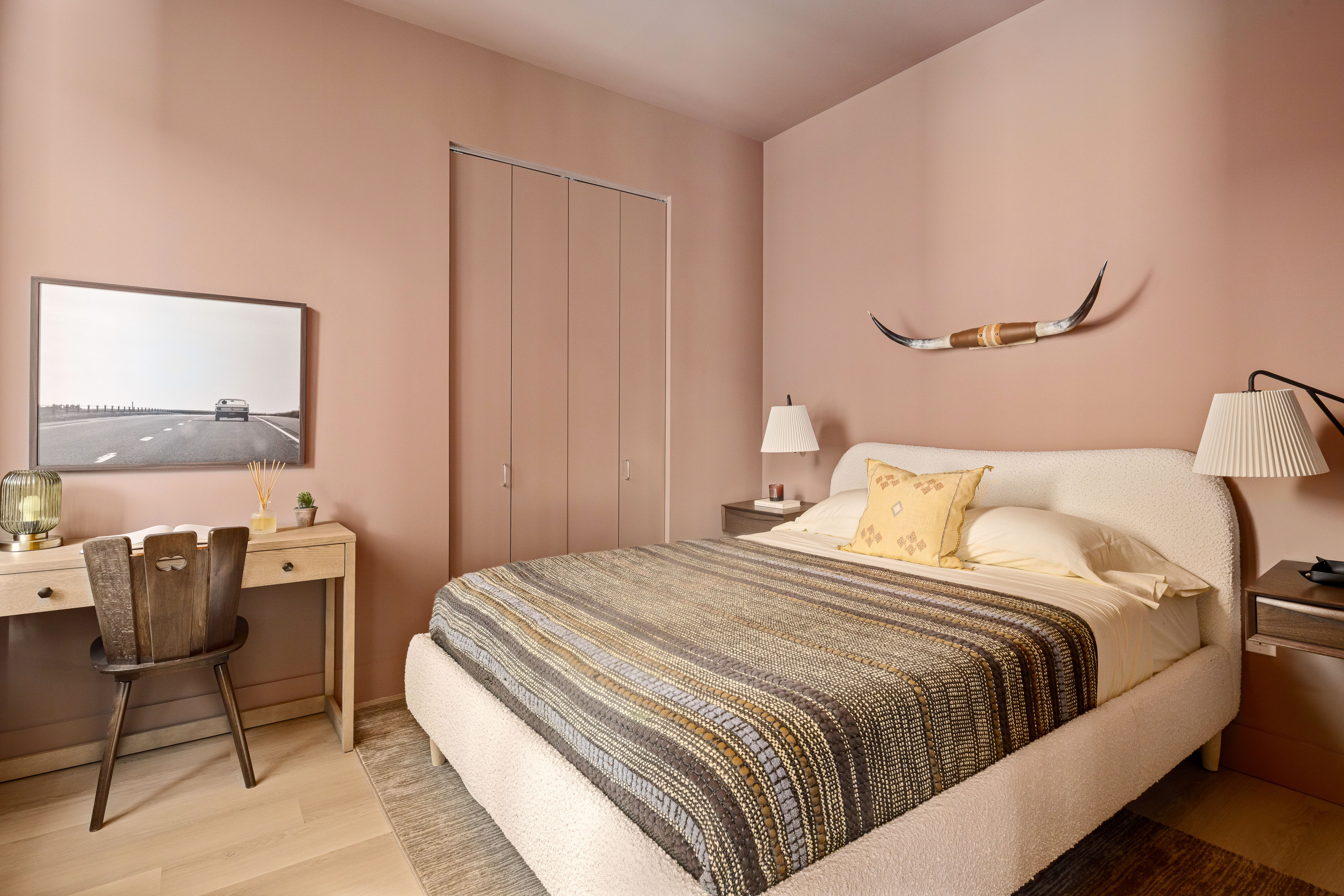 a bedroom with a bed a chair and painting on the wall