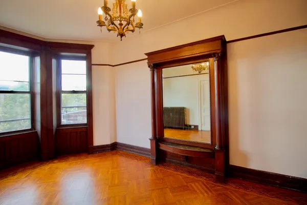 a view of an empty room with a window and wooden floor