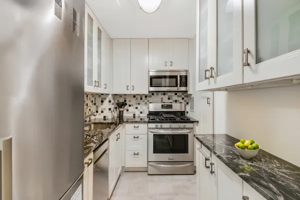 a kitchen with stainless steel appliances granite countertop a stove a sink and a white cabinets