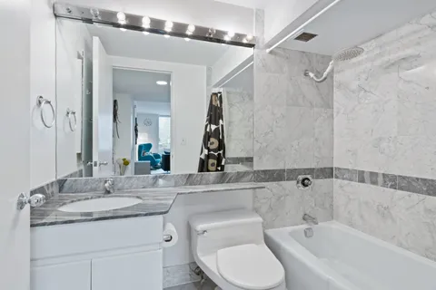 a bathroom with a granite countertop sink toilet and shower