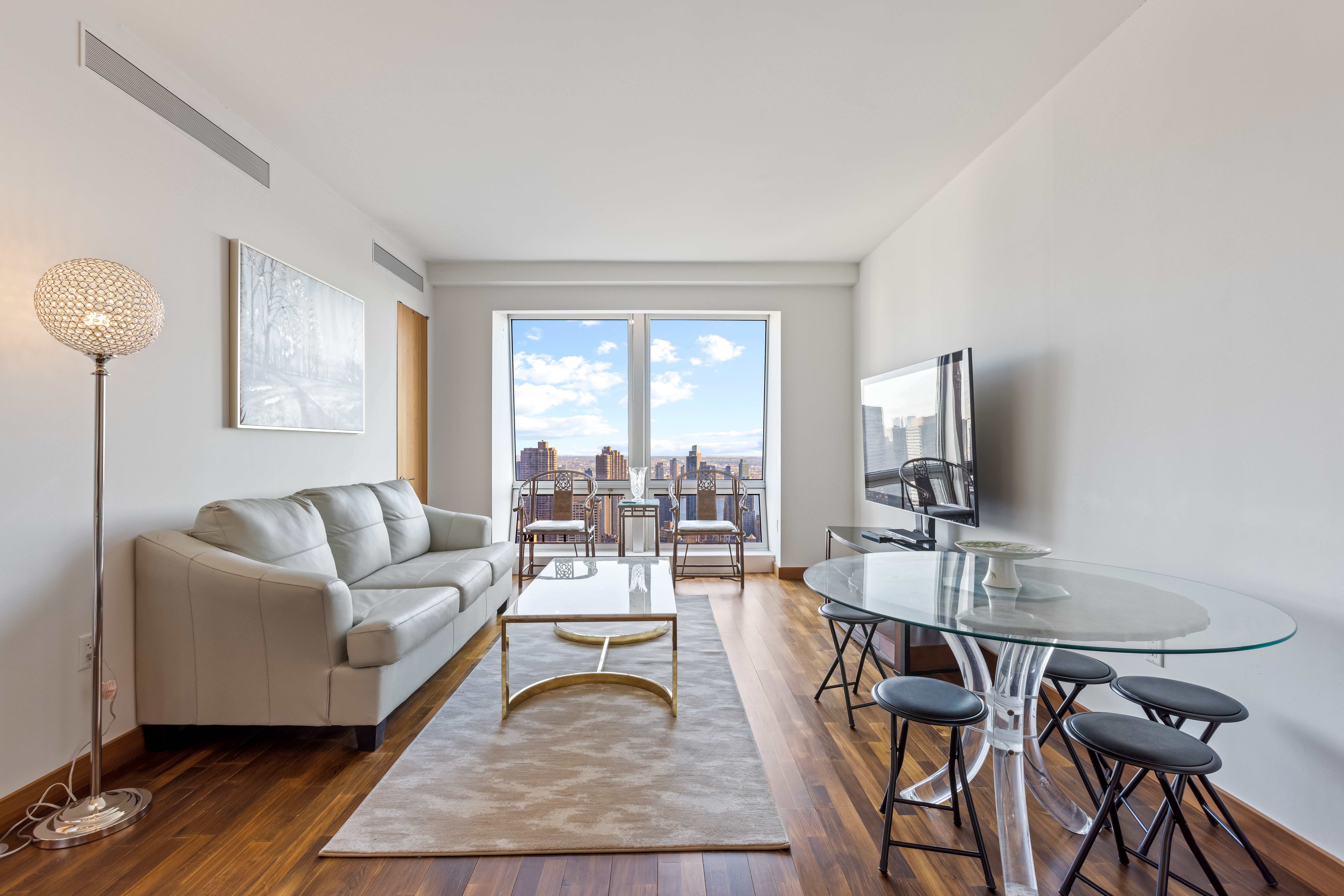 400 5th Avenue, Unit 49C Manhattan, NY 10018 - Photo 2 of 21 a living room with furniture a flat screen tv and a large window
