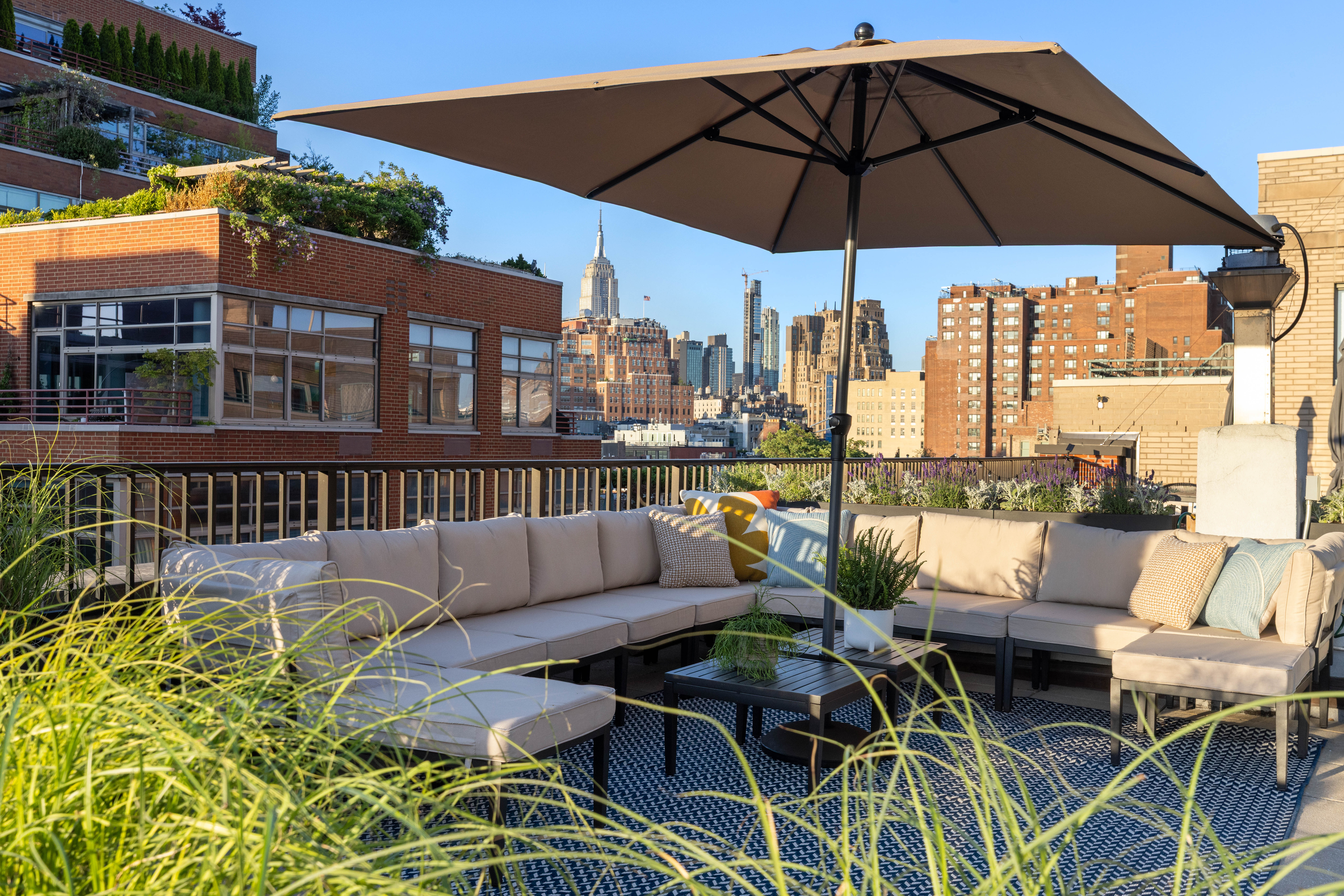 130 Jane Street, Unit 5/6F Manhattan, NY 10014 - Photo 21 of 23 a view of a patio with couches table and chairs under an umbrella