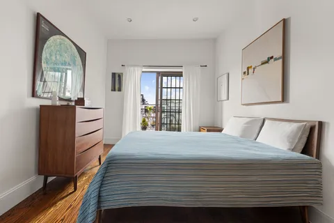 a bedroom with a bed cabinets and a window