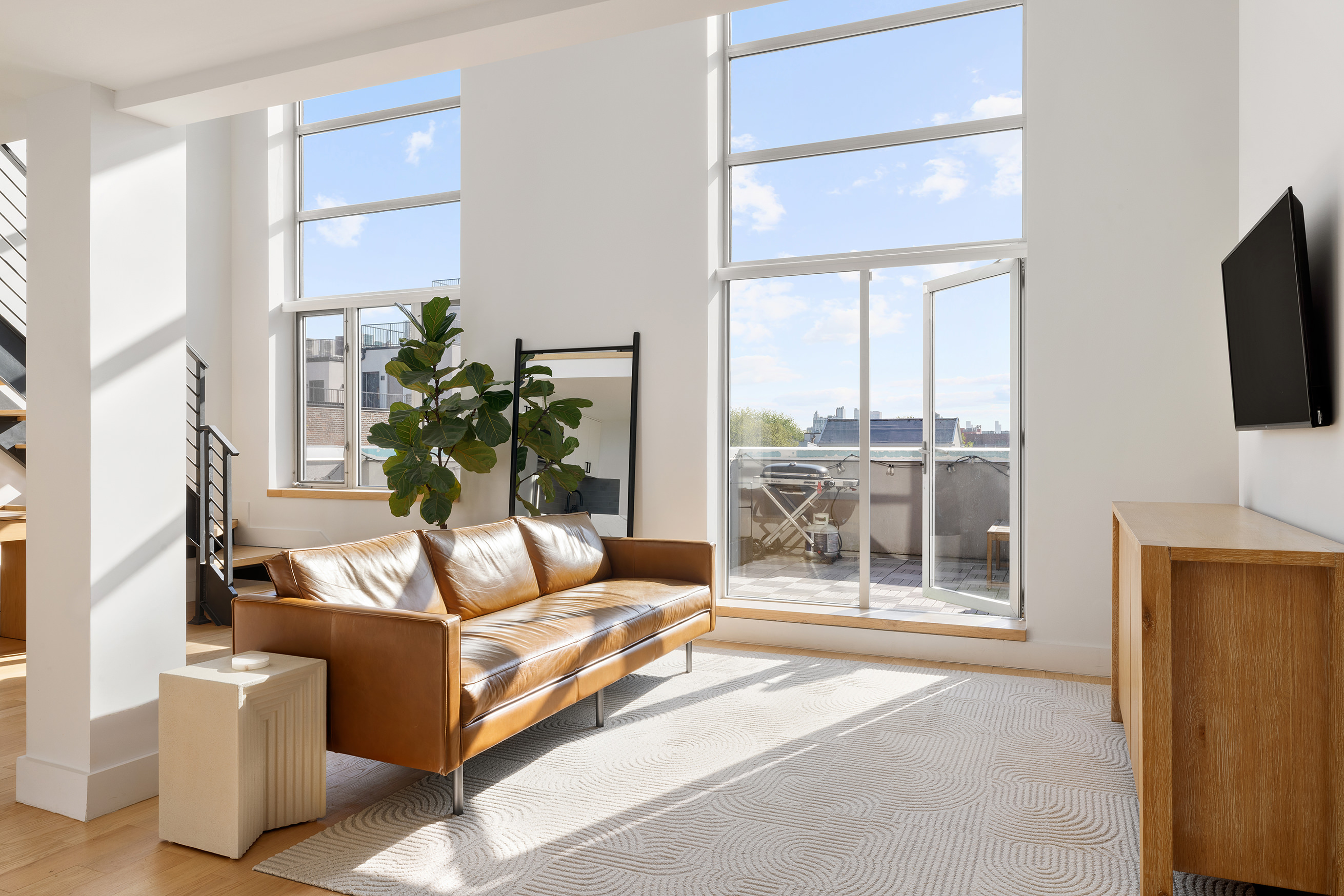 109 Waverly Avenue, Unit 4B Brooklyn, NY 11205 - Photo 4 of 14 a living room with furniture a flat screen tv and a floor to ceiling window