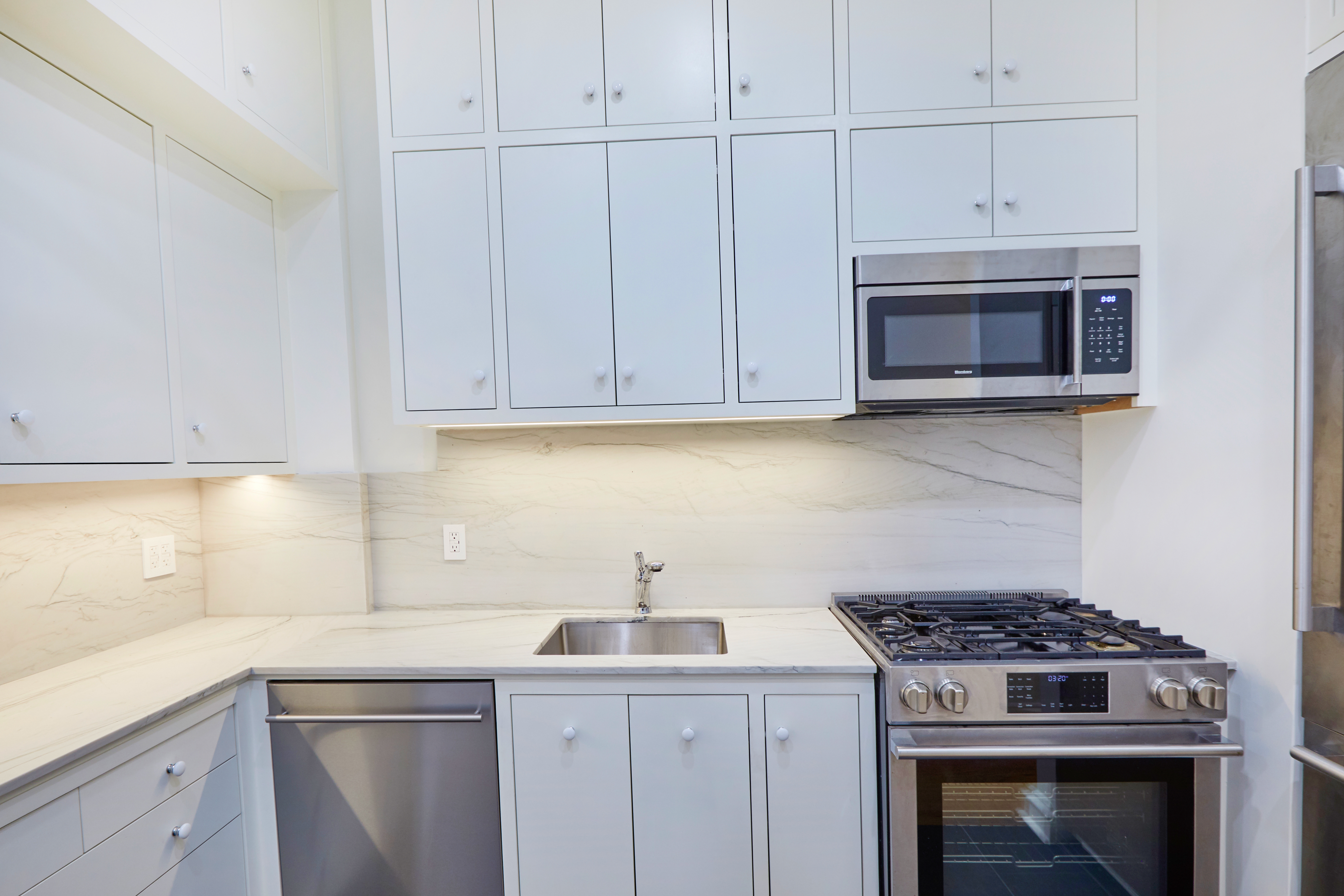 157 East 75th Street, Unit 1E Manhattan, NY 10021 - Photo 13 of 21 a kitchen with granite countertop white cabinets and stainless steel appliances