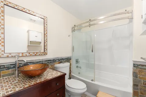 a bathroom with a granite countertop sink a mirror a bathtub and shower
