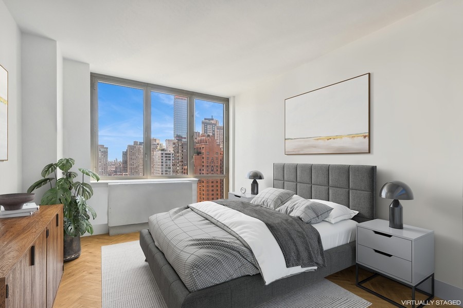2 Columbus Avenue, Unit 23A Manhattan, NY 10019 - Photo 6 of 10 a bedroom with a bed table flowerpot and a window
