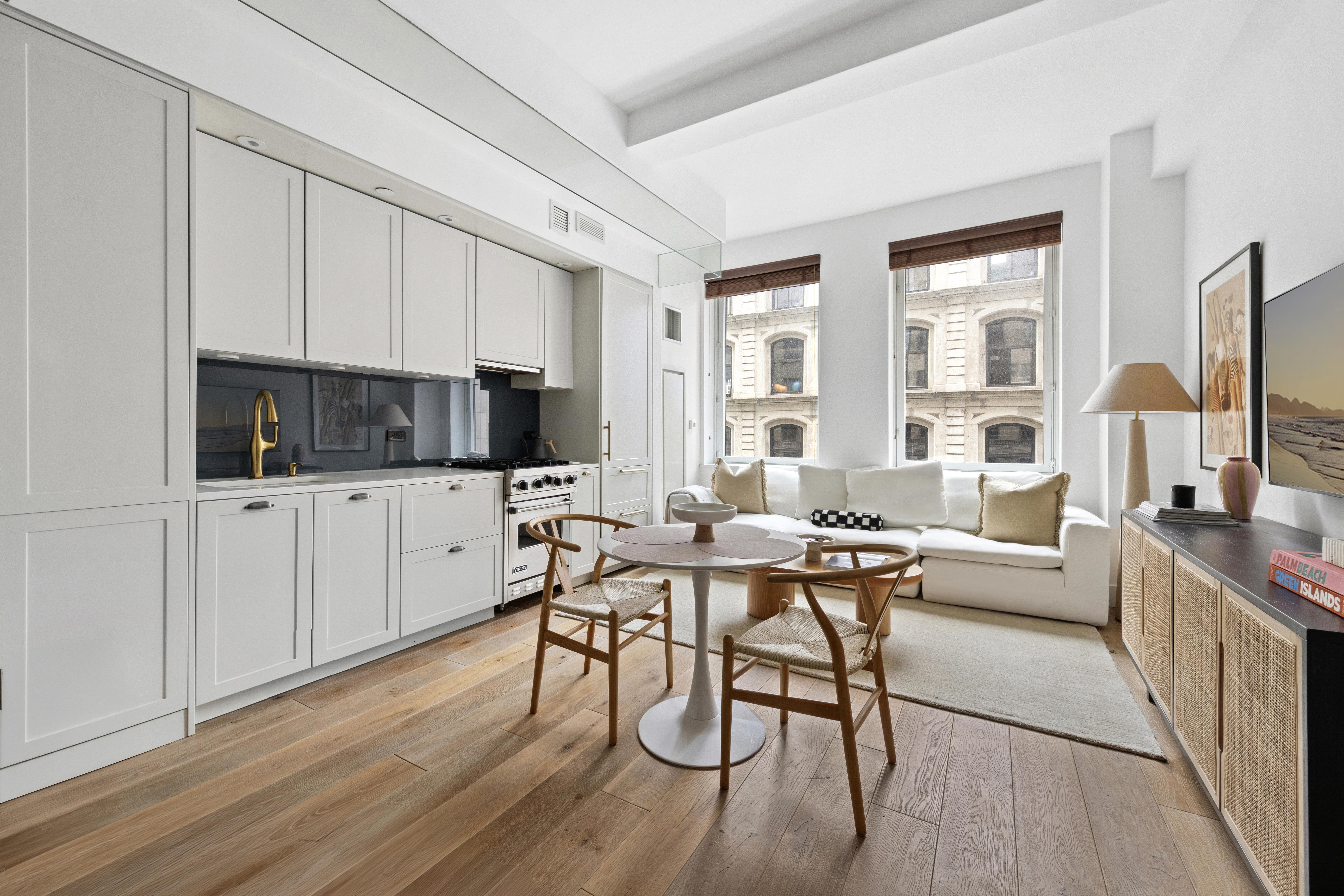 93 Worth Street, Unit 406 Manhattan, NY 10013 - Photo 1 of 11 a living room with furniture a flat screen tv and a wooden floor