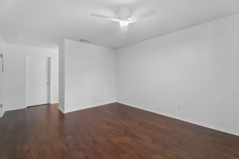 an empty room with wooden floor and fan