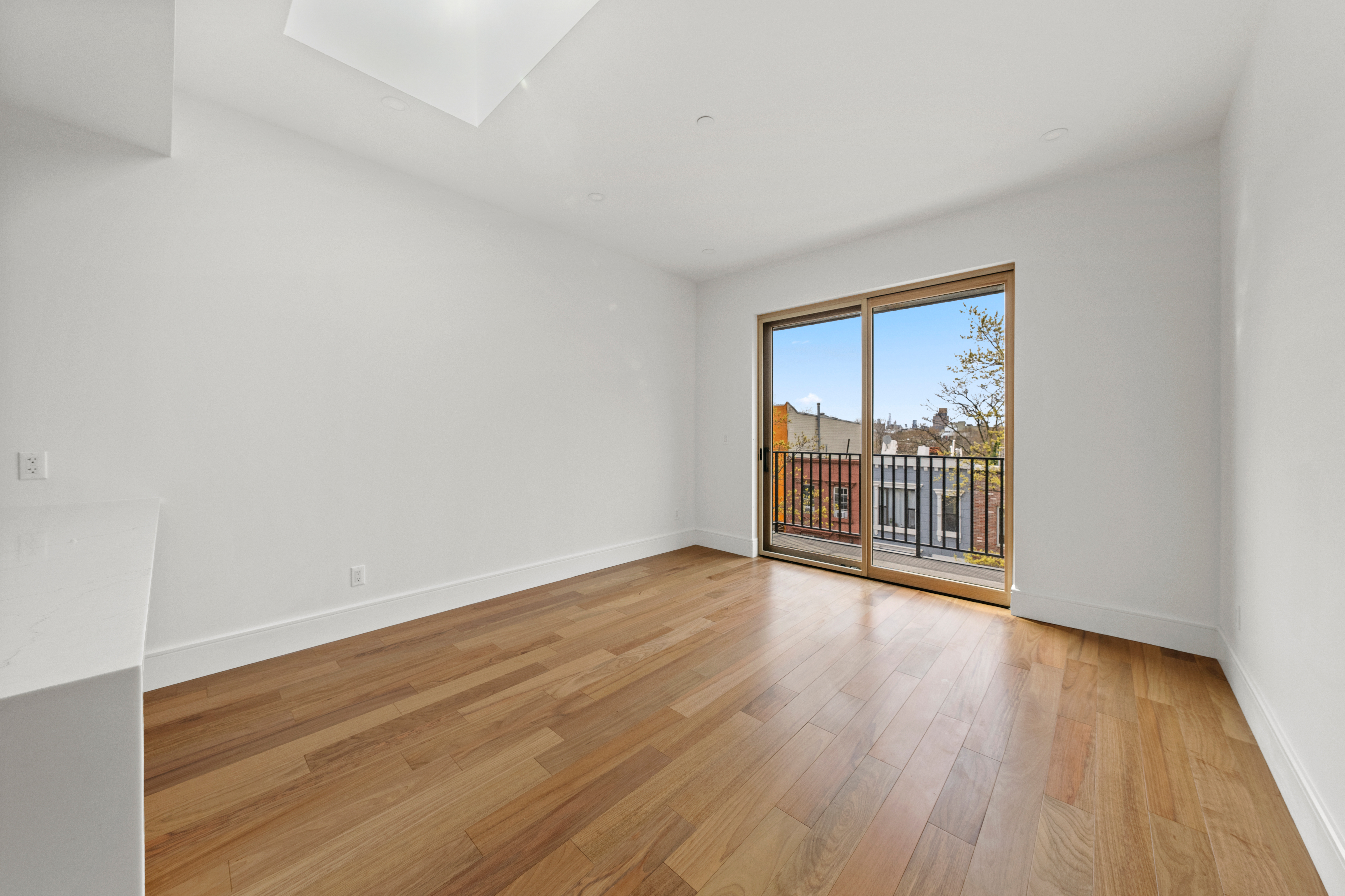 82 Cooper Street, Unit 3A Brooklyn, NY 11207 - Photo 13 of 17 a view of an empty room with wooden floor and a window