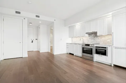 a kitchen with granite countertop a refrigerator and white cabinets