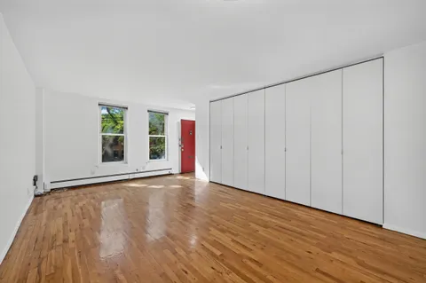 a view of an empty room with wooden floor and a window