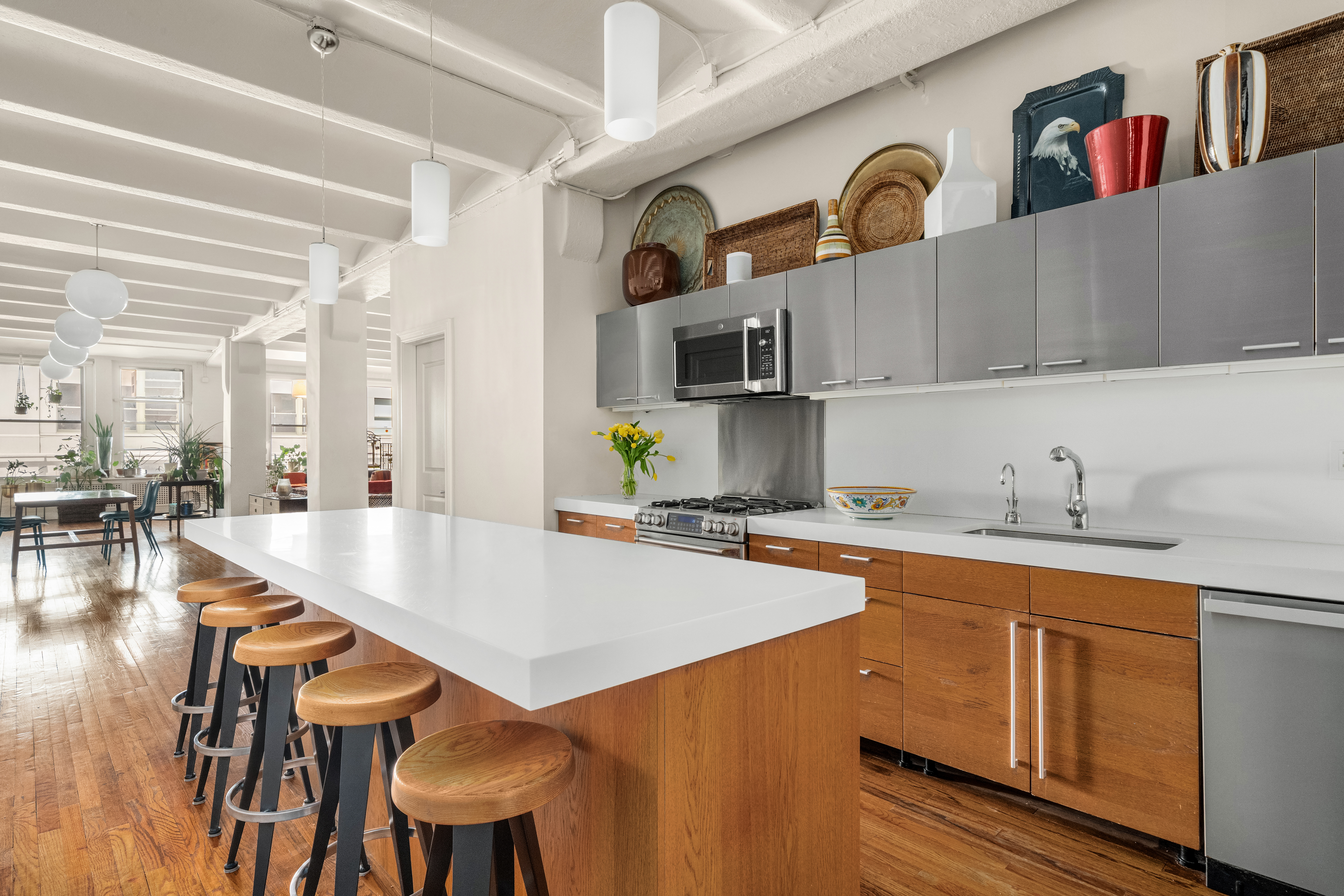 20-26 North Moore Street, Unit 4W Manhattan, NY 10013 - Photo 9 of 24 a kitchen with stainless steel appliances a table chairs in it and wooden floors