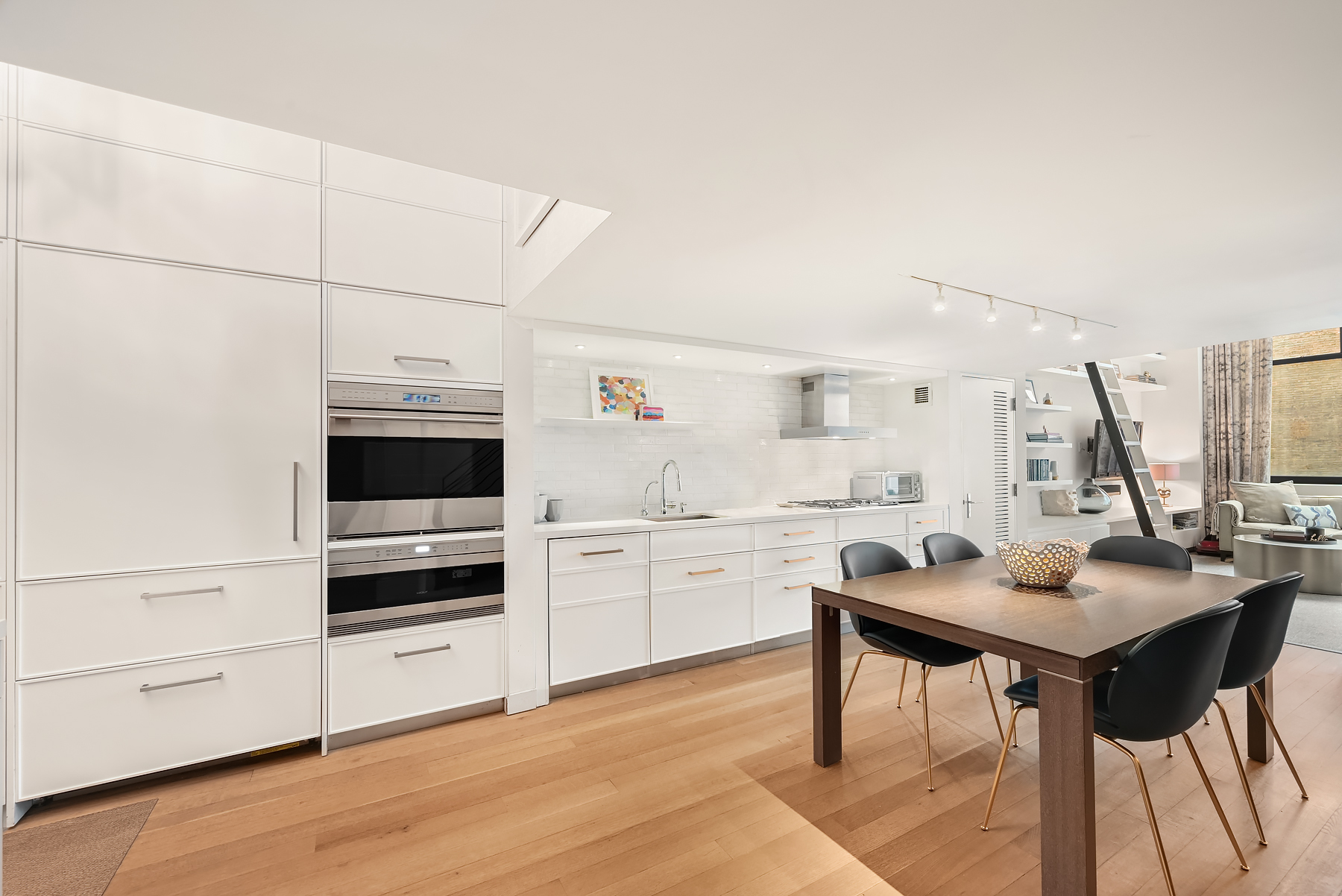 421 Hudson Street, Unit 318 Manhattan, NY 10014 - Photo 4 of 12 a kitchen with kitchen island white cabinets and stainless steel appliances