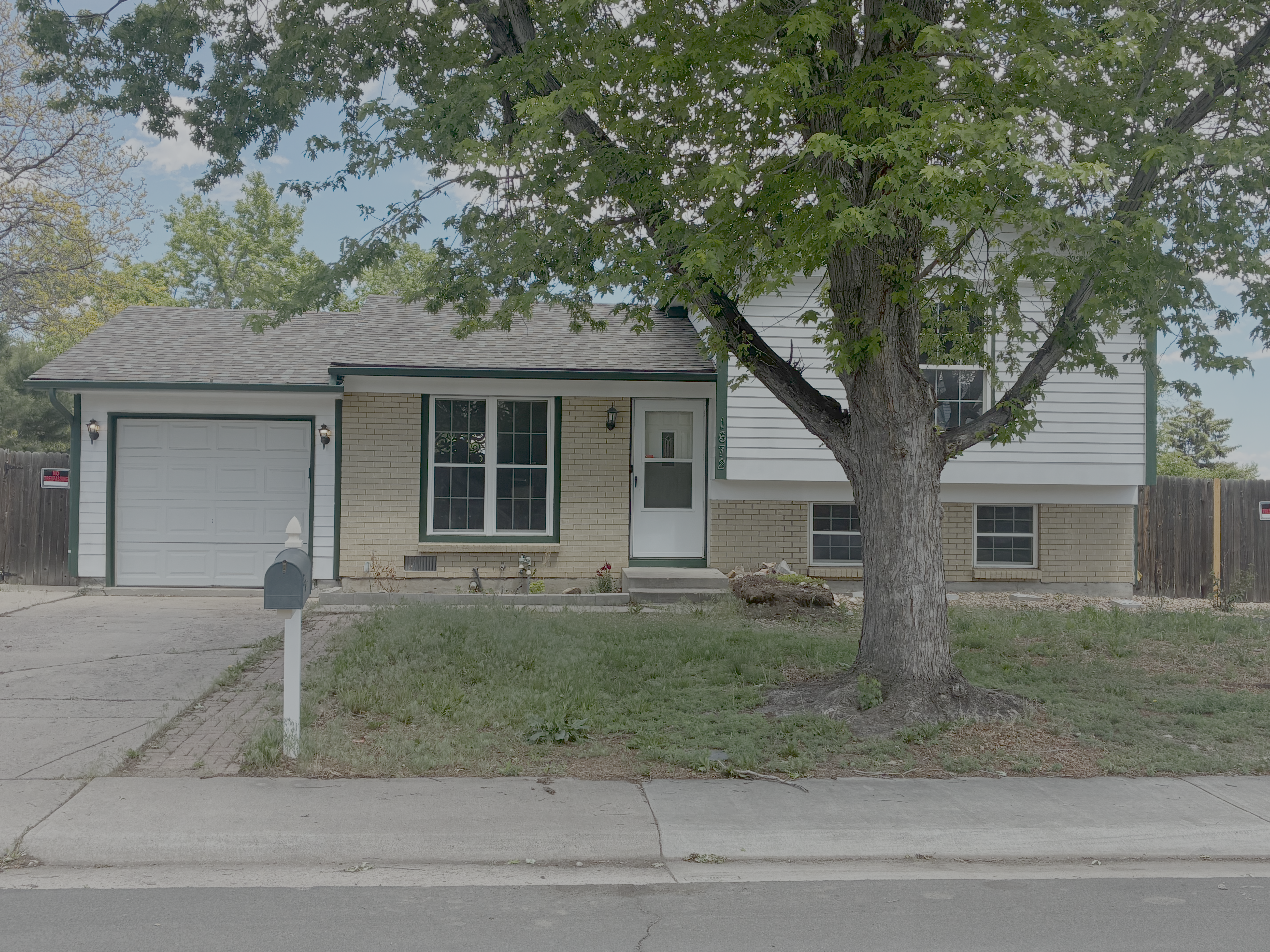 a front view of a house with a garden and trees