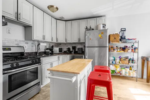 a kitchen with stainless steel appliances granite countertop a refrigerator sink stove and cabinets