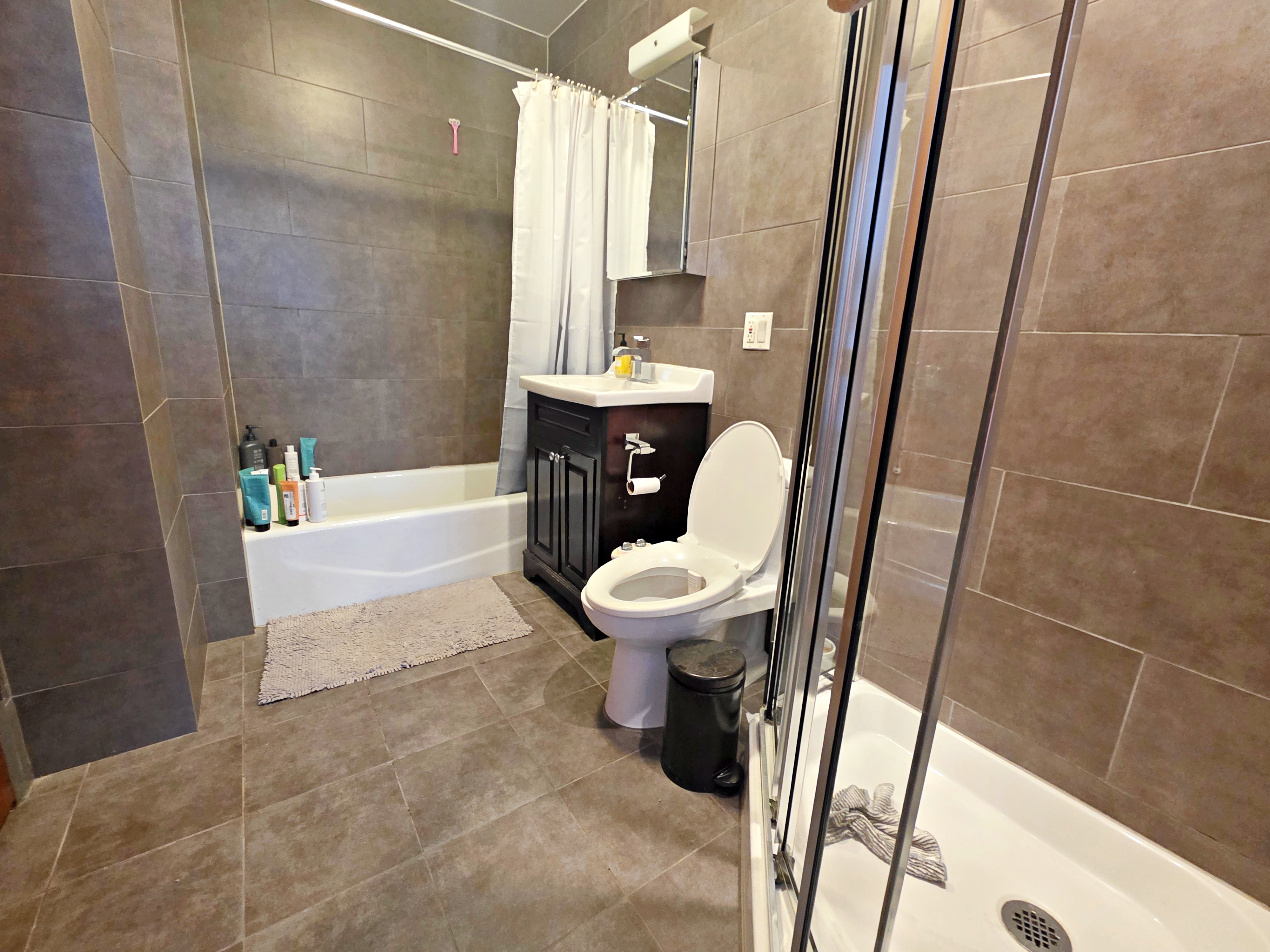713 Metropolitan Avenue, Unit 4R Brooklyn, NY 11211 - Photo 9 of 11 a bathroom with a sink a toilet a mirror and a tub