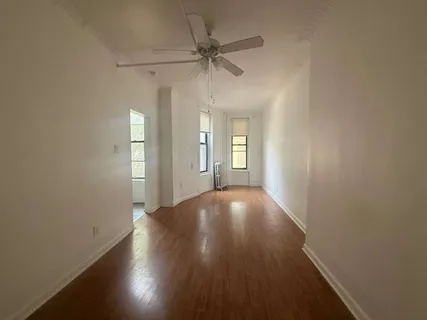an empty room with wooden floor fan and windows