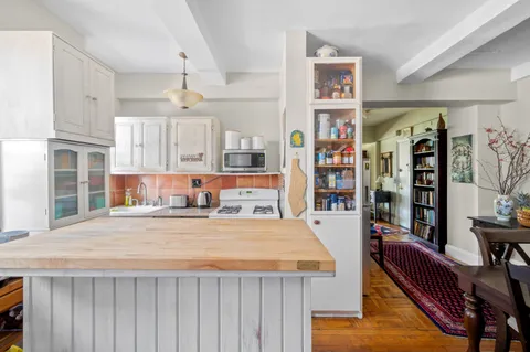 a living room with stainless steel appliances lots of furniture and wooden floors