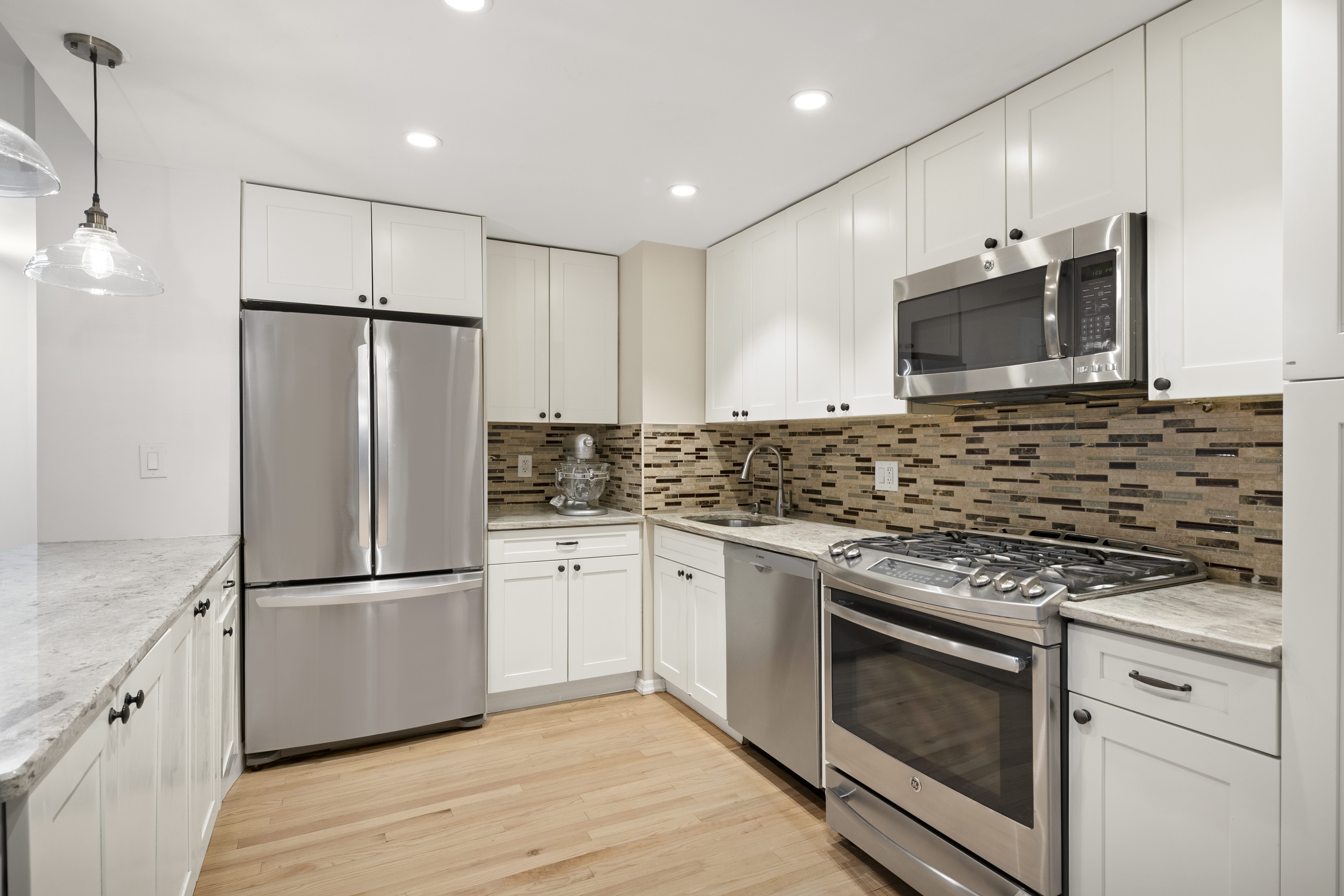 315 West 23rd Street, Unit 3E Manhattan, NY 10011 - Photo 2 of 10 a kitchen with granite countertop a refrigerator stove and microwave