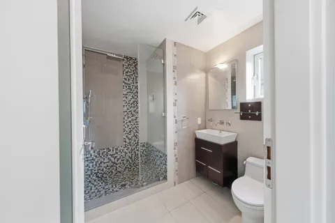 a bathroom with a double vanity sink toilet and shower