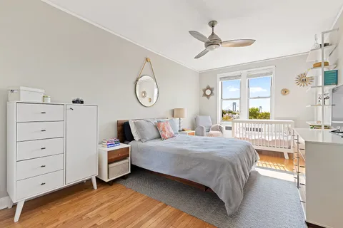 a bedroom with a bed a chandelier and a dresser