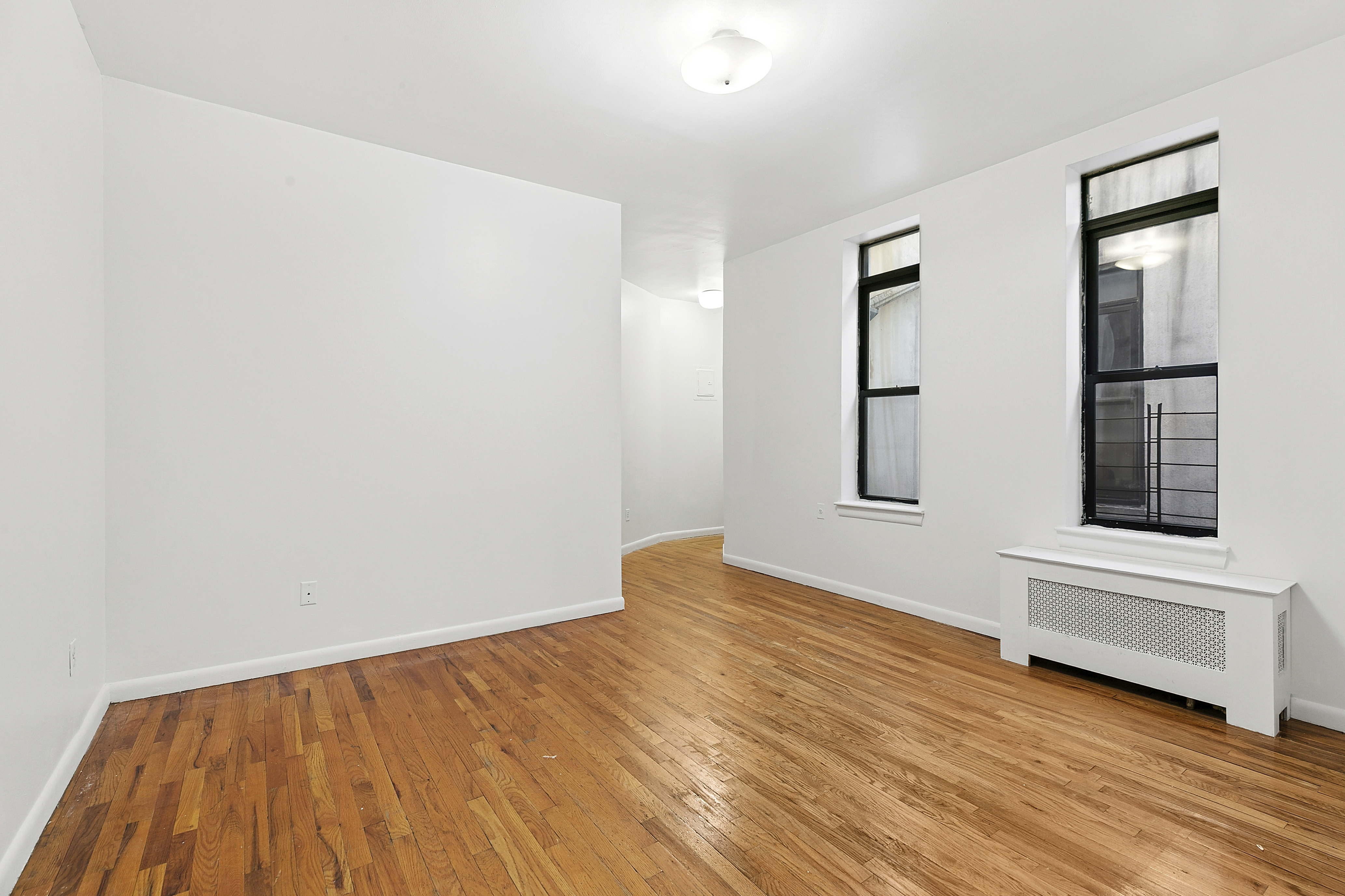 11 St Nicholas Avenue, Unit 5B Manhattan, NY 10026 - Photo 4 of 10 a view of an empty room with wooden floor and a window