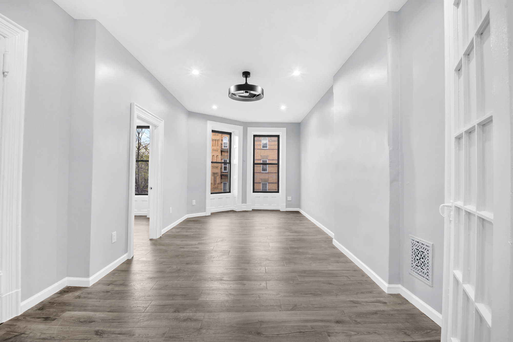 a view of an empty room with wooden floor and a window