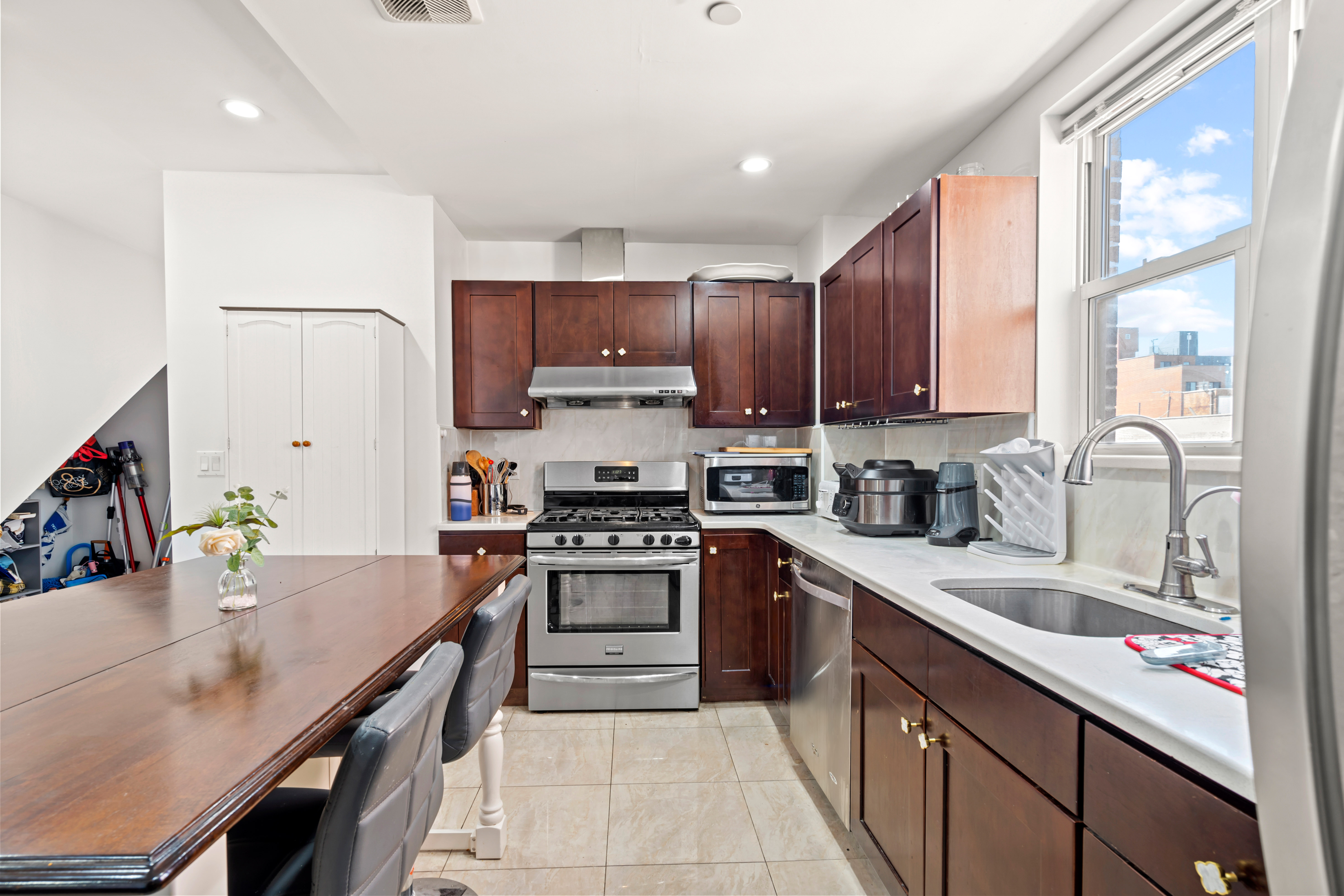 65-33 38th Avenue, Unit 5 Queens, NY 11377 - Photo 4 of 23 a kitchen with stainless steel appliances granite countertop a stove top oven a sink dishwasher and a refrigerator with wooden cabinets