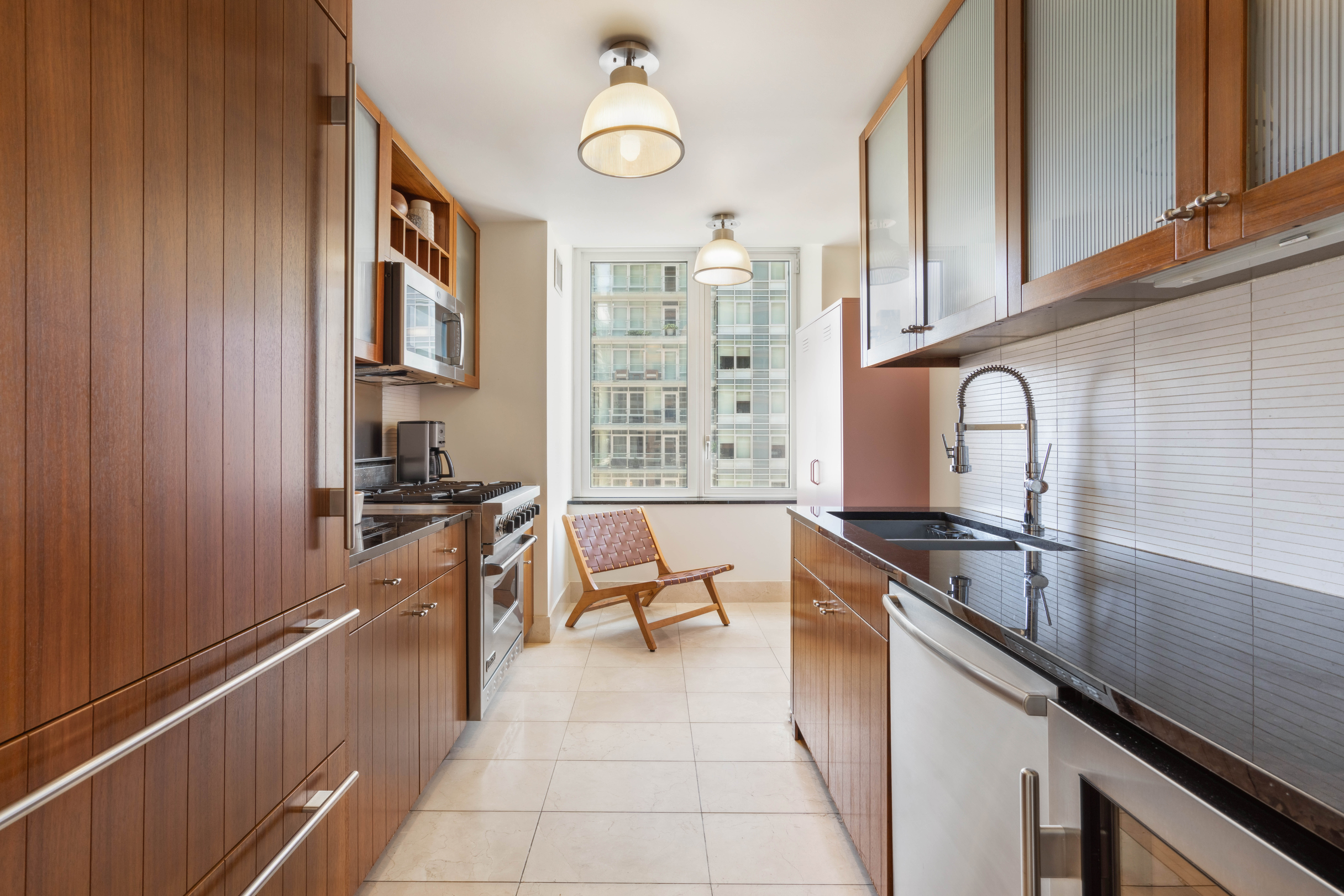 250 East 53rd Street, Unit 1402 Manhattan, NY 10022 - Photo 3 of 13 a kitchen with granite countertop a sink stove and cabinets