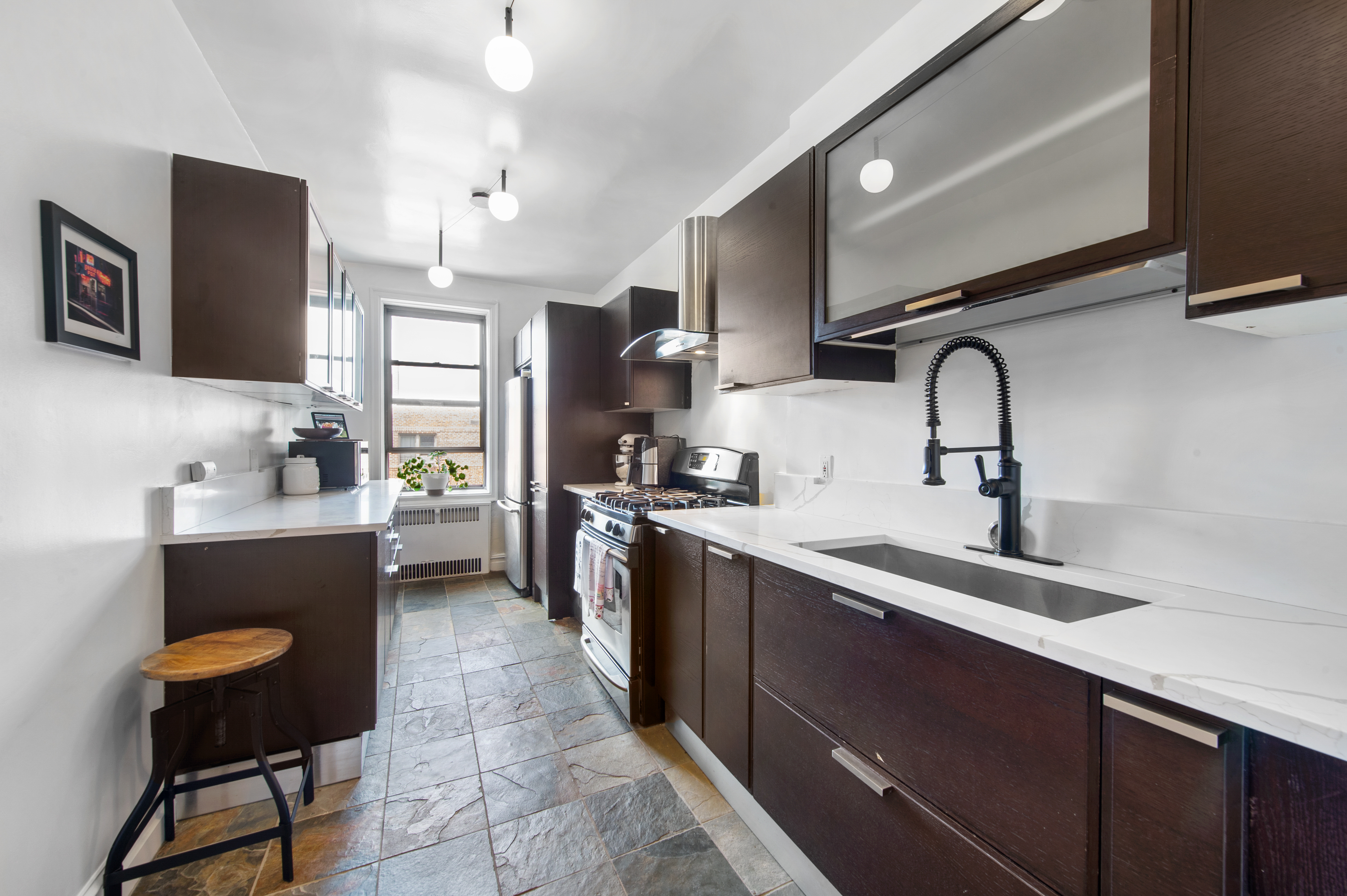 35-06 88th Street, Unit 6B Queens, NY 11372 - Photo 6 of 9 a kitchen with a sink cabinets and stainless steel appliances