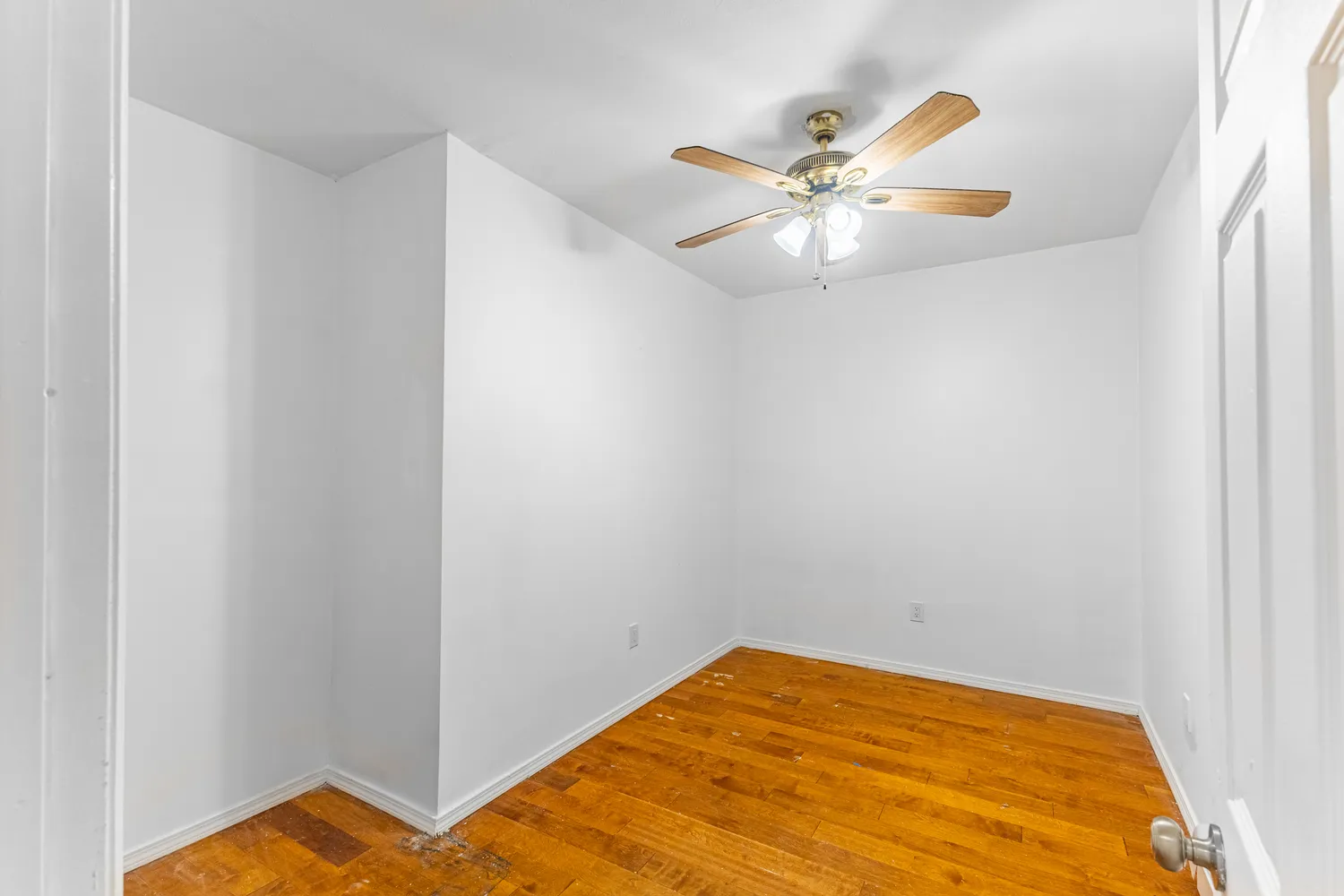 a view of a room with a ceiling fan and wooden floor