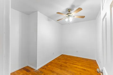 a view of a room with a ceiling fan and wooden floor