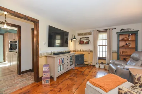 a living room with stainless steel appliances kitchen island granite countertop a rug a stove and a wooden floors