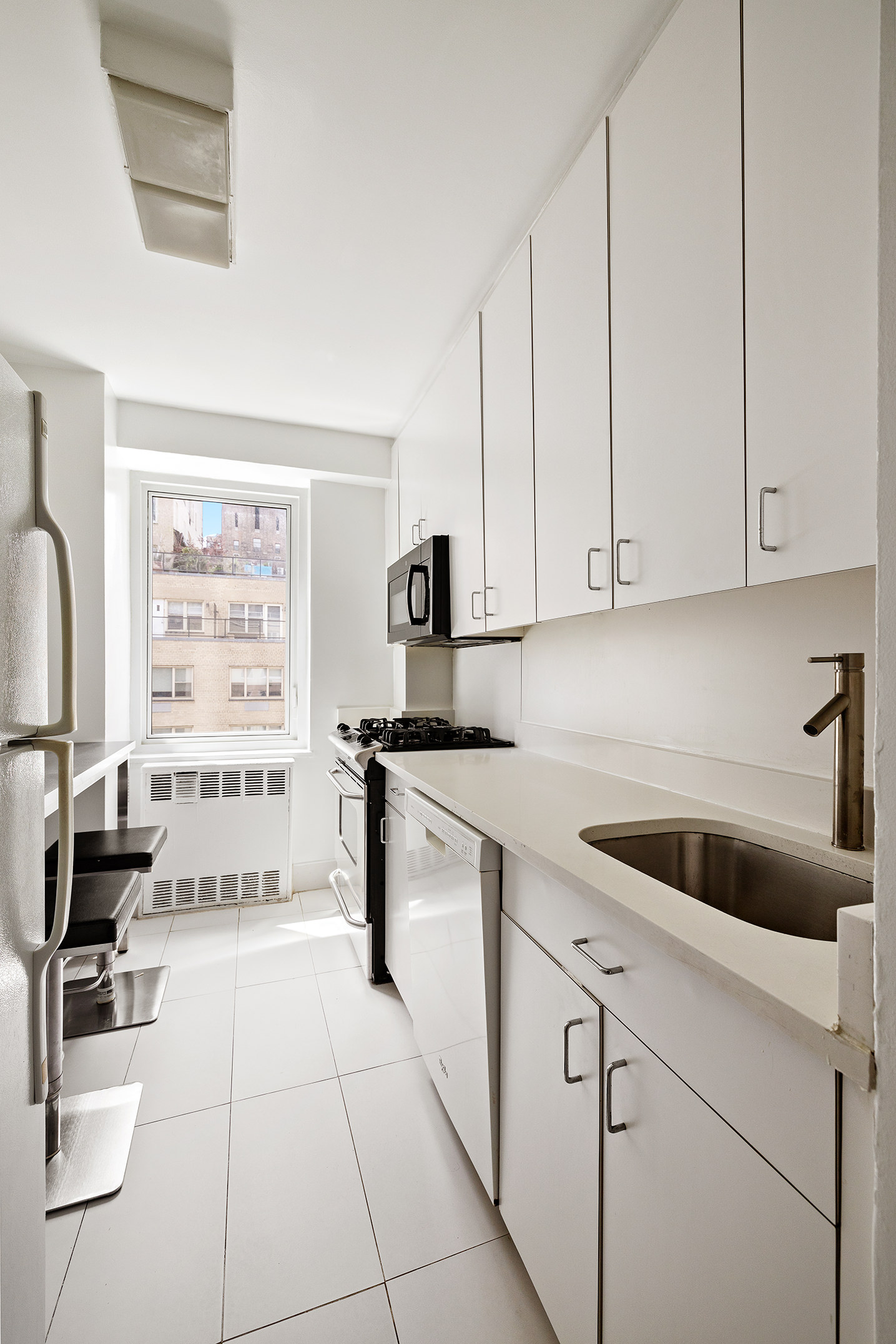 411 East 53rd Street, Unit 12D Manhattan, NY 10022 - Photo 11 of 15 a kitchen with a cabinets and white appliances