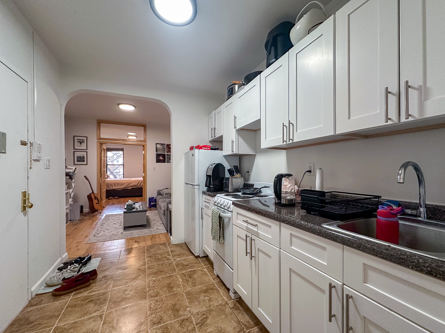 342 East 9th Street, Unit 3B Manhattan, NY 10003 - Photo 5 of 9 a kitchen with granite countertop a sink a stove and cabinets