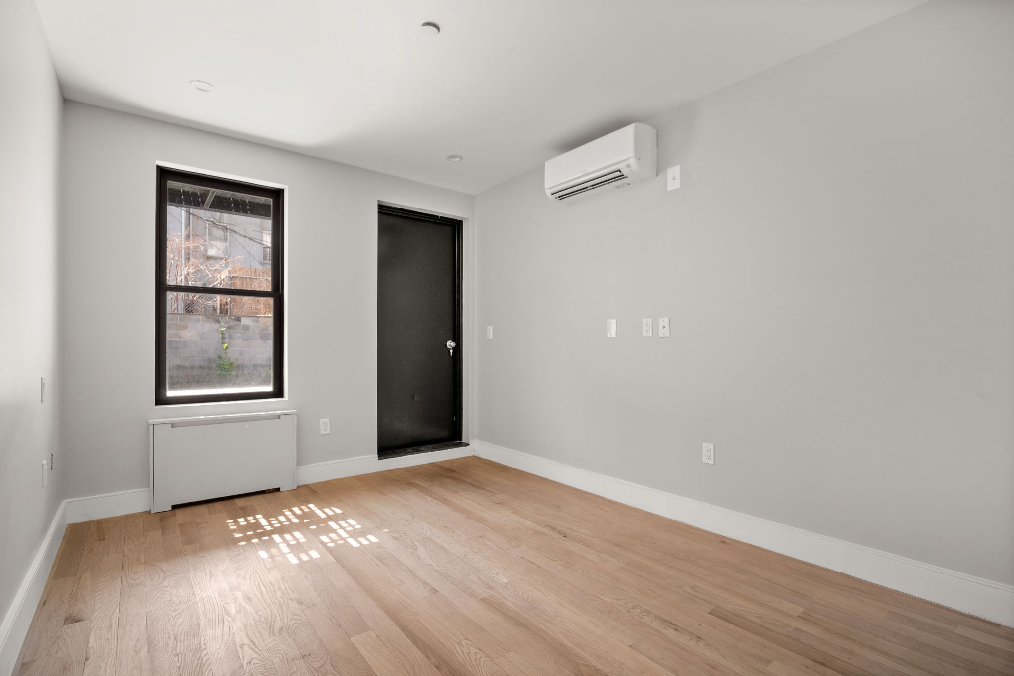 916 Greene Avenue, Unit 1 Brooklyn, NY 11221 - Photo 5 of 9 an empty room with wooden floor and windows