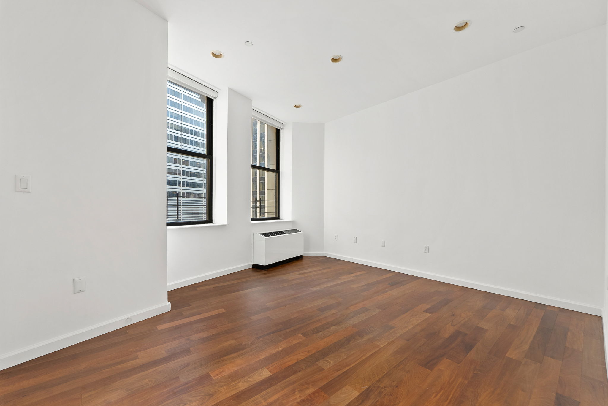 1 Wall Street Court, Unit 1405 Manhattan, NY 10005 - Photo 9 of 19 a view of an empty room with wooden floor and a window