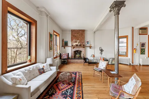 a living room with furniture large window and wooden floor