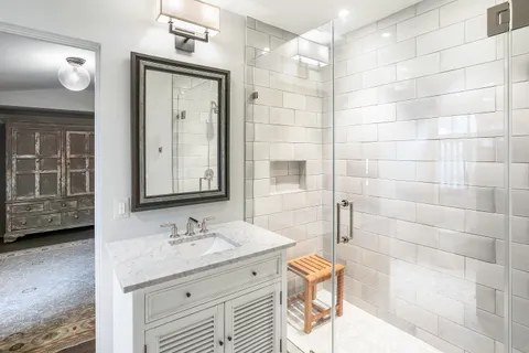 a bathroom with a granite countertop sink a toilet a mirror and shower