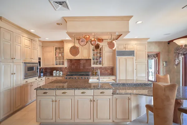 a kitchen with stainless steel appliances granite countertop a stove a sink and white cabinets