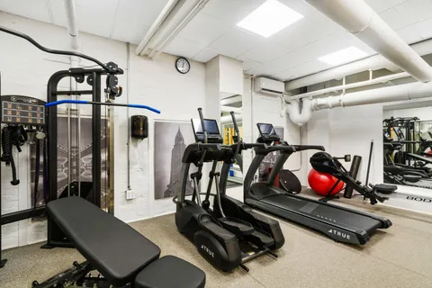 a room with gym equipment and wooden floor